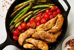 chicken, asparagus and tomatoes in a skillet with seasoning on the side