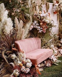 a pink couch sitting on top of a lush green grass covered field next to tall white flowers