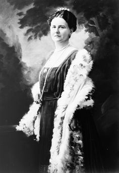 an old black and white photo of a woman in a dress with feathers on it