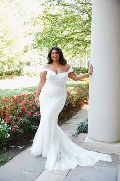 a woman in a white wedding dress posing for the camera with her arms out and hands behind her back