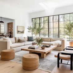 a living room filled with lots of furniture and large windows in the back ground area