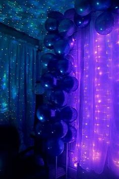 purple and blue balloons are hanging from the ceiling in front of a curtain with stars on it