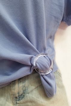 a person wearing a blue shirt with a ring on it's belt and jeans