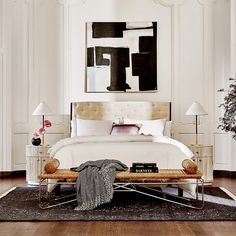 a bedroom with a white bed, black and white painting on the wall above it