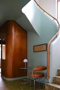 a room with a spiral stair case next to a table and chair in front of a window