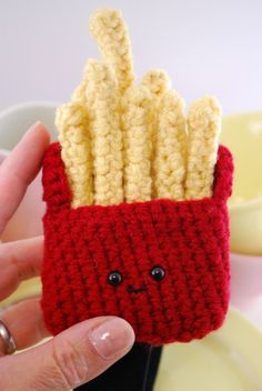 a hand holding up a small crocheted red and yellow container with french fries in it