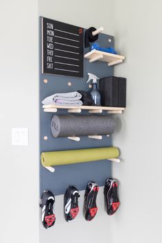 there is a wall mounted shelf with various items on it and some shoes hanging up against the wall