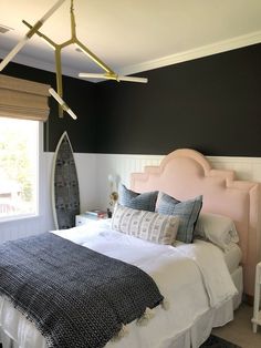 a bed room with a neatly made bed and a surfboard hanging from the ceiling