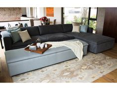 a living room with a large sectional couch and coffee table on the floor in front of it