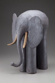 an elephant statue made out of concrete with tusks on it's back