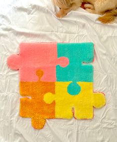 a dog laying on top of a bed next to a puzzle piece