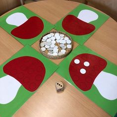 a wooden table topped with paper cut outs covered in white and red circles next to a bowl of coins