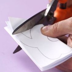 someone cutting paper with scissors on top of it