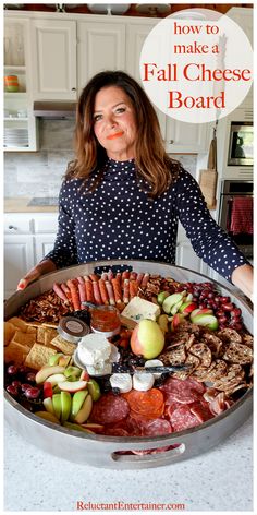 a woman standing in front of a large platter of meats and vegetables with the words how to make a fall cheese board