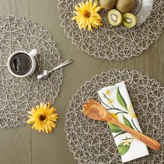 two serving trays with yellow flowers and fruit on them next to a cup of coffee