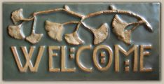 a metal sign that says welcome hanging from a tree branch