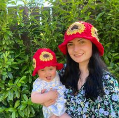 a woman holding a baby wearing red hats