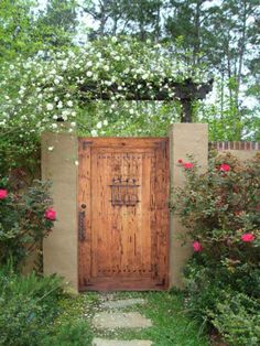 a wooden door in the middle of a garden with roses growing around it and an arch