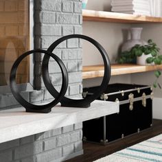 two black rings sitting on top of a white shelf next to a fireplace in a living room