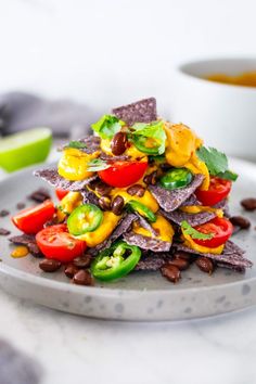 a plate filled with nachos and vegetables on top of a marble countertop