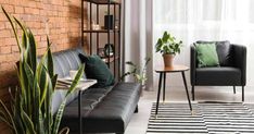 a living room with black leather couches and potted plants on the side table