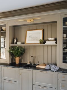 a kitchen with white cabinets and black counter tops, including a potted plant in the corner