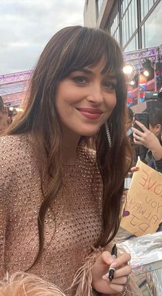 a woman holding a cell phone in her right hand and posing for the camera with a sign that says i love you always