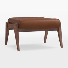 an upholstered bench with wooden legs and a brown leather seat pad on the back