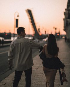 a man and woman are walking down the sidewalk at sunset or dawn with their arms around each other