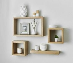 three wooden shelves on the wall with vases and other items sitting on top of them