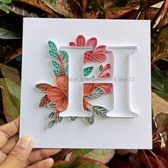 a hand holding up a card with the letter j on it and flowers in front