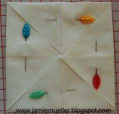 an origami quilt block with pins and leaves on it, ready to be sewn