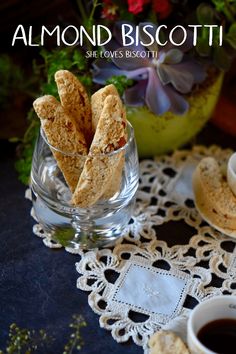 the cover of almond biscotti, with two cups of coffee and flowers in the background