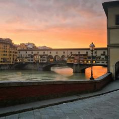 a bridge over a river with buildings on both sides and a lamp post in the foreground