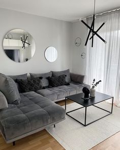 a living room with grey couches and round mirrors on the wall above them, along with a black coffee table