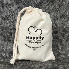 a drawstring bag sitting on top of a gray carpet with the words happily written in black