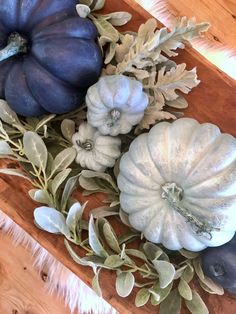 some blue pumpkins and leaves on a wooden table