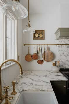 a kitchen with marble counter tops and gold faucets hanging on the wall above the sink