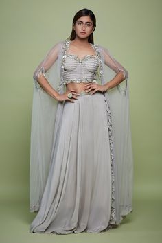 Grey lehenga with sequin embellished waistband. Paired with a padded corset crop top with scallop lace and floral embroidery in cutdana, sequins and beads embroidery. Comes along with a cape.
Components: 3
Pattern: Embroidery
Type Of Work: Scallop, Floral, Cutdana, Sequins, Beads
Neckline: Sweetheart Neck
Sleeve Type: Sleeveless
Fabric: Net, Crepe, Crepe Lining
Color: Grey
Other Details: 
Padded
Attached inner lining
Ruffle border cape with floral embroidery
Occasion: Sangeet - Aza Fashions Grey Lehenga, Cape For Women, Net Embroidery, Beads Embroidery, Corset Crop Top, Beaded Neckline, Pattern Embroidery, Fashion App, Lace Crop Tops