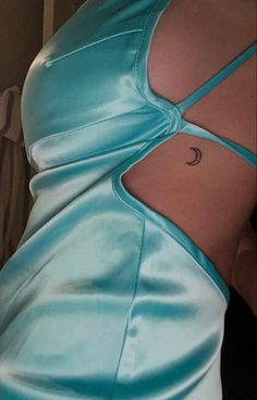 the back of a woman's dress with a crescent tattoo on her left side