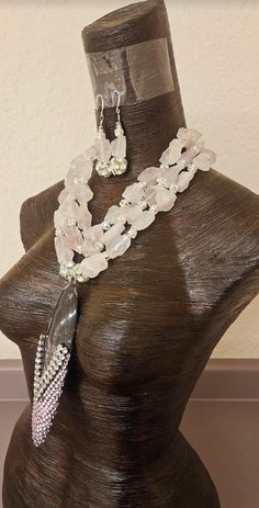 Soft baby pink rough dusty rose quartz gemstones along with silver tone rhinestone balls are featured in this one-of-a-kind multi strand statement necklace pendant - chest piece. This avant garde piece would be gorgeous worn on the mother of the bride or mother of the groom. The prehistoric black and white fossil pendant measures 7" x 2.25" and is bejeweled with extra large silver tone rhinestones and soft baby pink Swarovski crystals (I will send additional pink crystals in the event some should fall off). Two 1" silver tone rhinestone balls flank each side of the pendant. The rough quartz necklace adjusts from 19-23" and is finished in the back with pink aurora borealis crystals cubes. It closes with silver tone hardware, a fancy "s" hook clasp and a 4" extender chain. A rhinestone ball Rose Quartz Jewelry With Natural Stones For Wedding, Rose Quartz Jewelry For Jewelry Making, Pink Crystal Jewelry With Stones, Pink Rose Quartz Jewelry For Party, Rose Quartz Natural Stones Jewelry For Jewelry Making, Elegant Rose Quartz Beaded Jewelry, Unique Pink Jewelry With Stones, Pink Rose Quartz Party Jewelry, Elegant Beaded Rose Quartz Jewelry