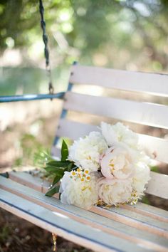 a bouquet of flowers sitting on top of a wooden bench next to a park swing