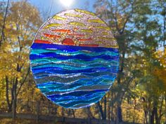 a stained glass sun catcher hanging in front of trees