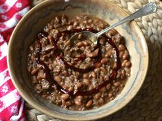 a bowl filled with beans and sauce on top of a red and white checkered table cloth