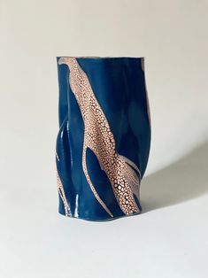 This image shows the Swirly Vase Blue and Peach by Astrid Öhman in stoneware with an uneven, wavy shape. The vase is predominantly dark blue with an intricate design resembling tree branches or veins in a contrasting beige color that appears cracked, creating a textured pattern. The background is plain and light. Monster Wall, Vase Blue, Raku Pottery, Handmade Vase, Vintage Objects, Wall Tile