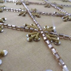 a close up view of a beaded cross on a table cloth with other beads