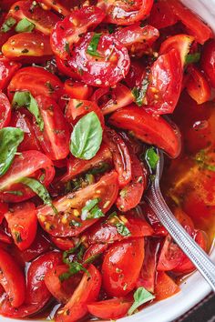 a white bowl filled with sliced tomatoes and basil