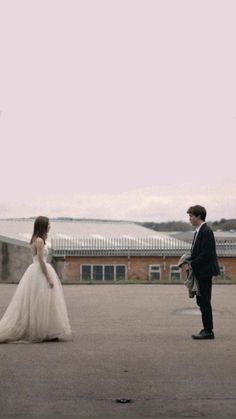 a woman in a wedding dress standing next to a man