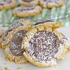 cookies with chocolate and powdered sugar are on a white surface next to green napkins