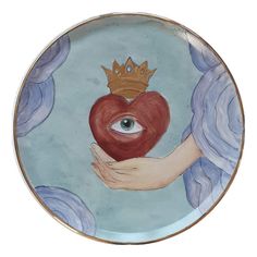 a hand holding a heart with a crown on it and an eye in the middle